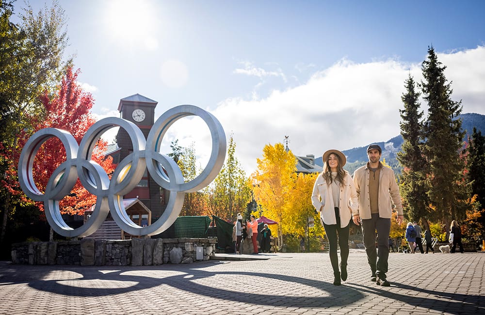 Couple walking near Olympic Rings statue in Downtown Whistler, British Columbia
