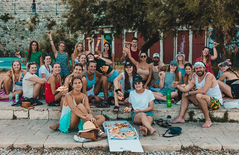Topdeck youth travel group in Croatia sitting on street with pizza.