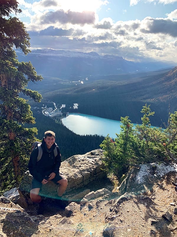 Male hiker at lookout in Banff National Park with Lake Louise down below.