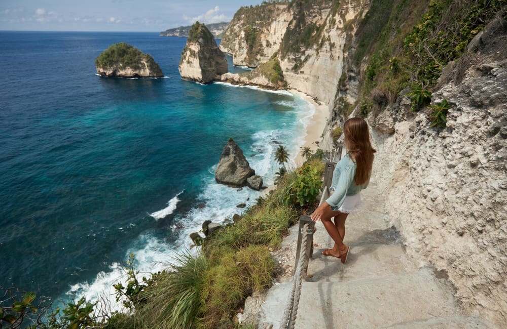 Female traveller standing on clifftop steps looking at the ocean in Bali – top 2025 Easter destinations