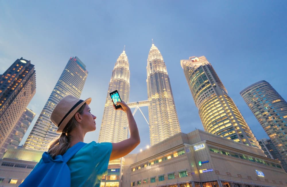 Female tourist taking photo of Petronas Towers in Kuala Lumpur, Malaysia.