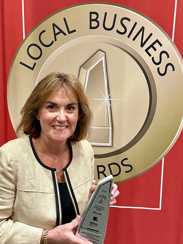 Northshore Travel Director Sam Young holding a 2024 Local Business Award.