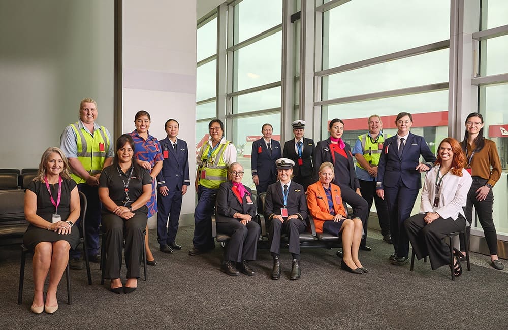 Female Qantas group employees seated in an airport showing the diversity of roles available in the aviation industry.