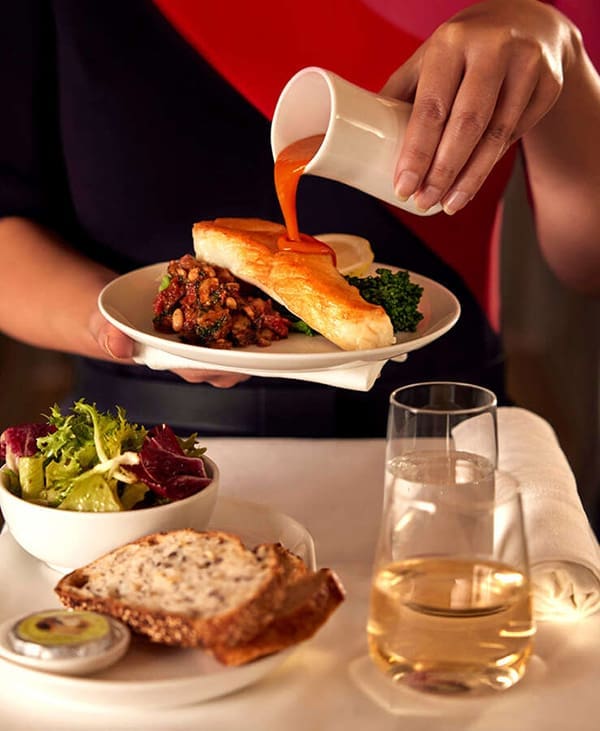 Qantas flight attendant serving meal in international Business Class.