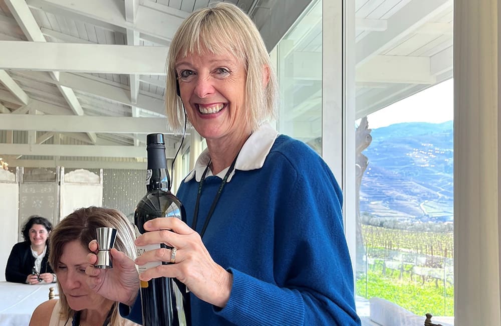 Woman holding port bottle at a cocktail-mixing session in a Douro Valley wine estate, Portugal.