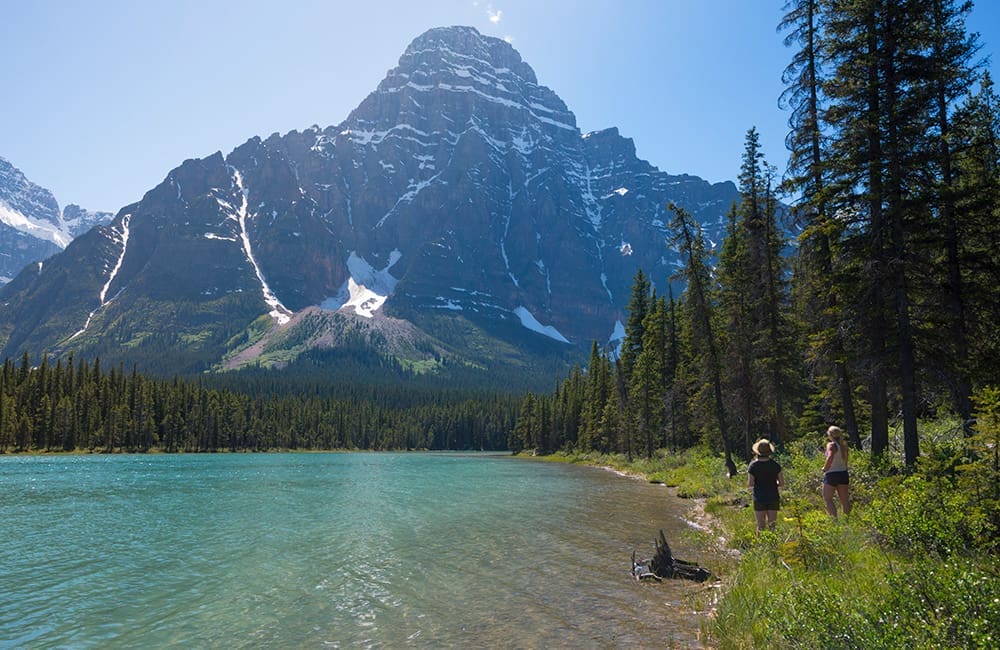Two women walking at edge of lake in Banff National Park – Parks Canada. Image: William Patino