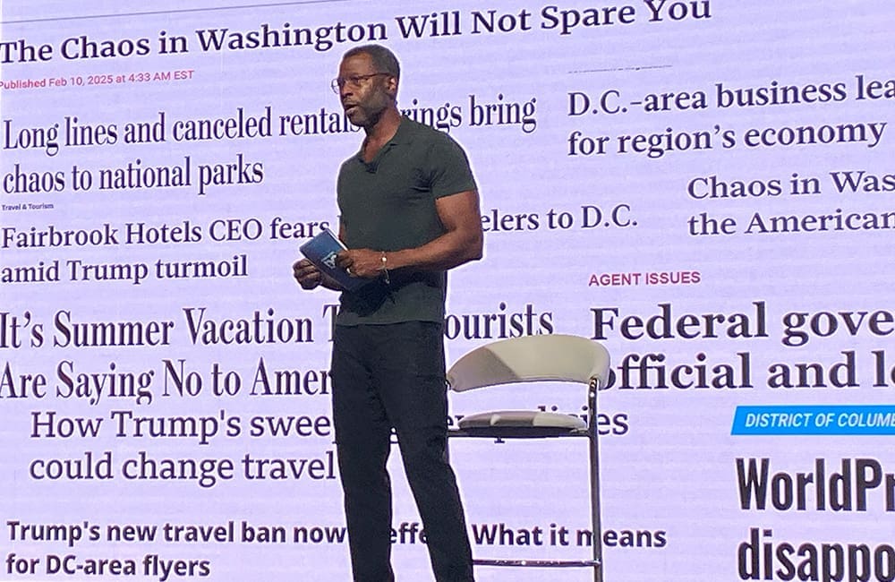 Destination DC President & CEO Elliott Ferguson against a slide backdrop of black-and-white newspaper headlines at IPW25. Image: Cassie Tannenberg