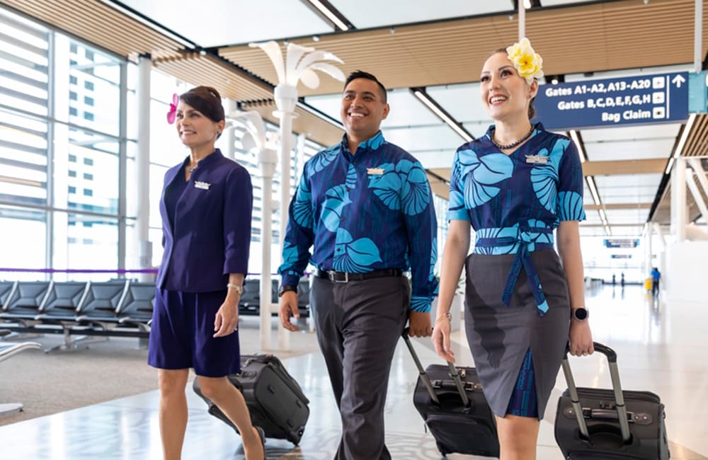 Hawaiian Airlines flight attendants with luggage walking through Mauka concourse at Honolulu Airport