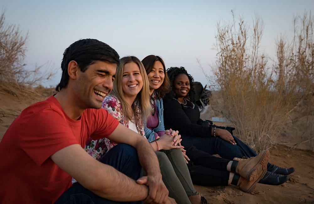 Intrepid Travel Trip Leader with group sitting in Kyzylkum desert yurt camp in Uzbekistan.