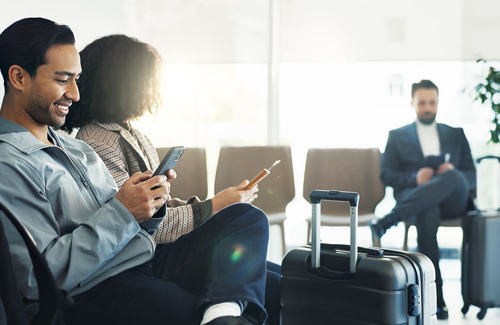 Travellers in airport with smartphones – use AI to book holidays
