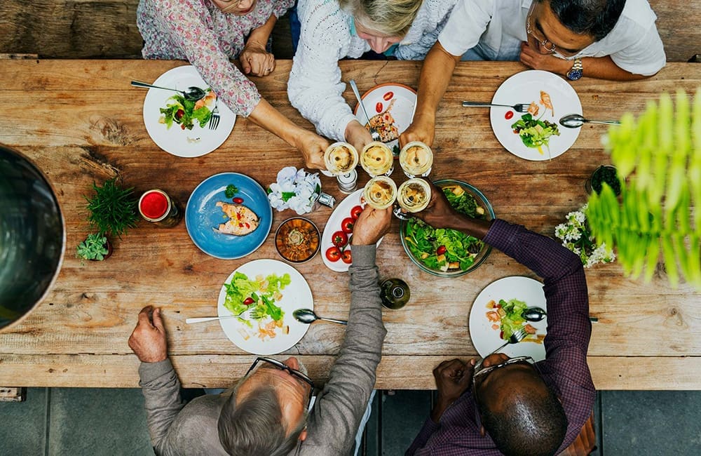 Top-down image of people dining with wine at shared meals table – Roam by Tauck