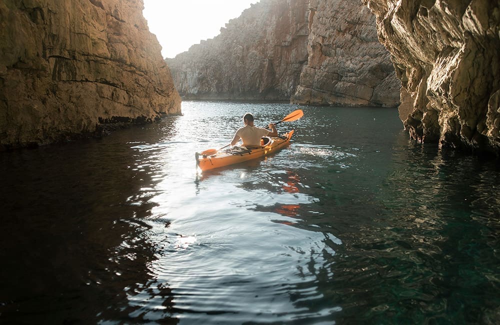 Man kayaking between rocks – Roam by Tauck