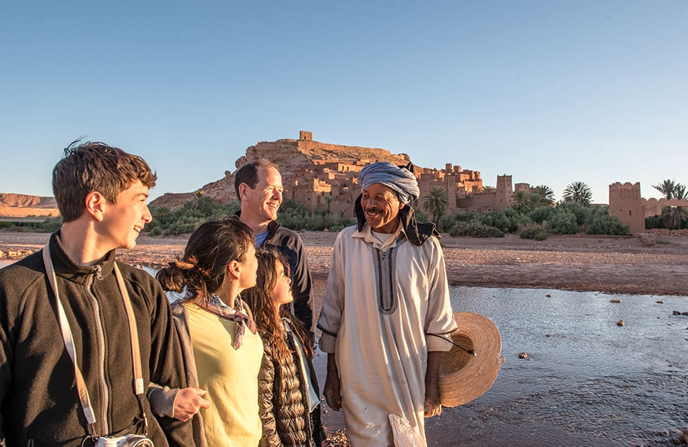 Family travelling with a local guide in the historic village of Aït Benhaddou in Morocco. Image: Intrepid Travel