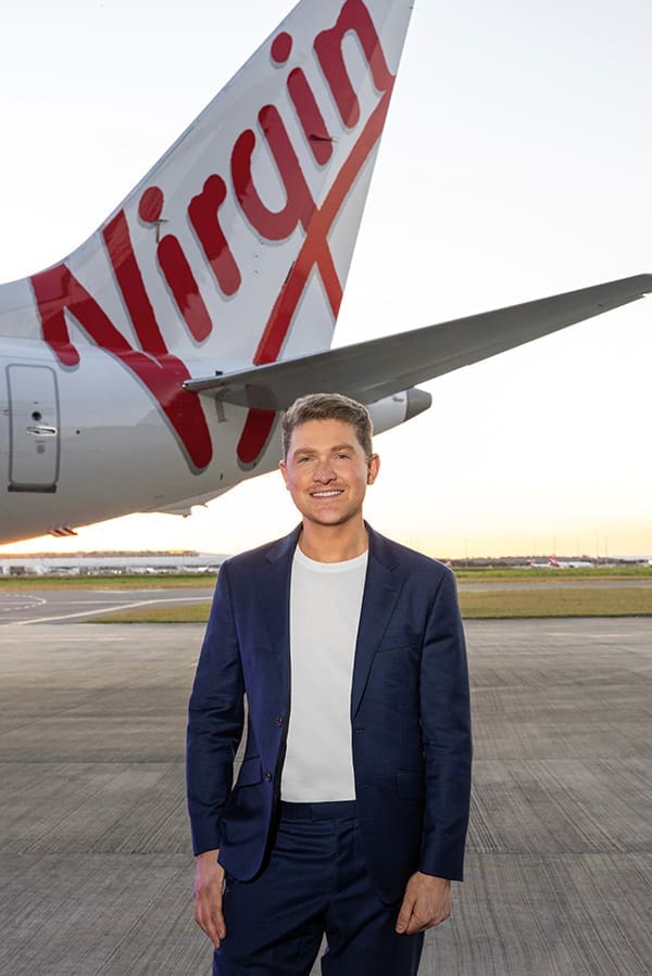 Virgin Australia Group Head of PR & Brand Matthew Ongarello on tarmac with aircraft tail.