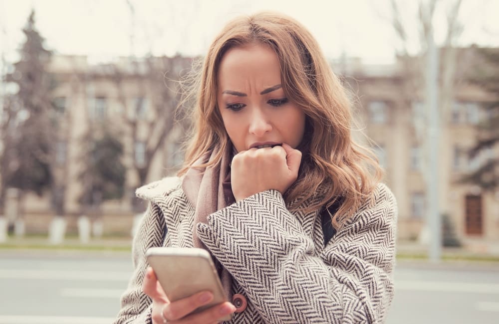 Shocked woman looking at mobile phone on street – mobile roaming charges.