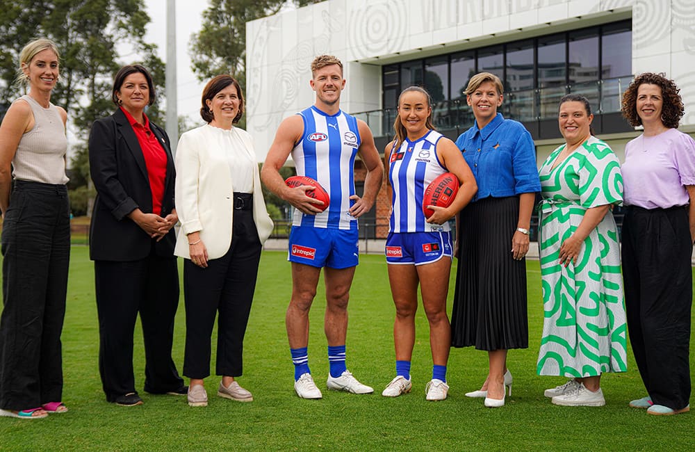 Intrepid Travel and North Melbourne teams at the club partnership announcement in March 2025, including Intrepid Travel VP Marketing USA Louise Laing, NMFC President Dr Sonja Hood, NMFC AFL Midfielder Luke Parker, NMFC AFLW Defender Nicole Bresnehan, NMFC CEO Jen Watt & Intrepid Travel Chief People & Purpose Officer Meegan Marshall.