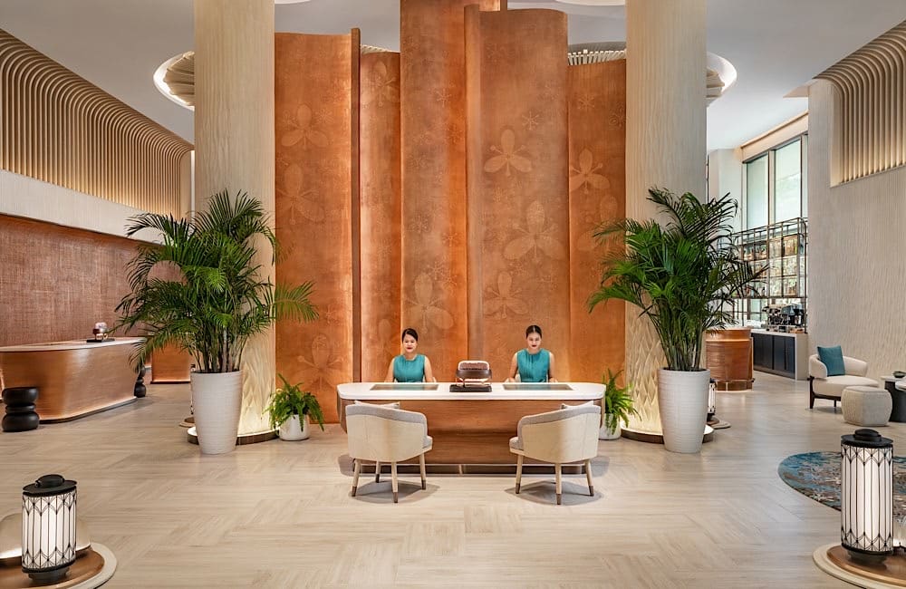 Staff welcome guests in a lobby designed as an open social space under the sugar palm canopy.
